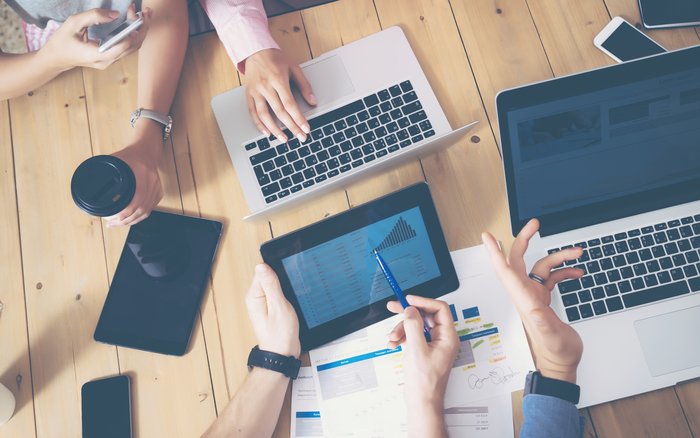 Generisches Büro, mehrere Hände die über einen Tisch greifen Laptops und Tablets auf dem tisch