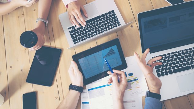 Generisches Büro, mehrere Hände die über einen Tisch greifen Laptops und Tablets auf dem tisch